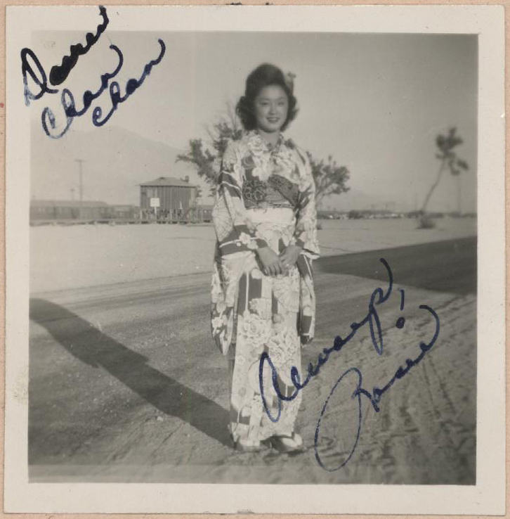 Rosie Maruki Kakuuchi poses in her kimono in front of barracks at Manzanar concentration camp. While many Japanese Americans had to leave cultural items like kimonos behind when they were forced into WWII concentration camps, some took the risk of bringing them along even though their luggage was severely restricted and scrutinized.