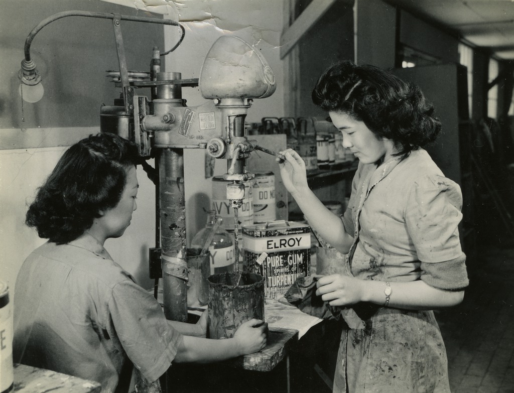 Black and white photo of two Nikkei women using a paint mixer.