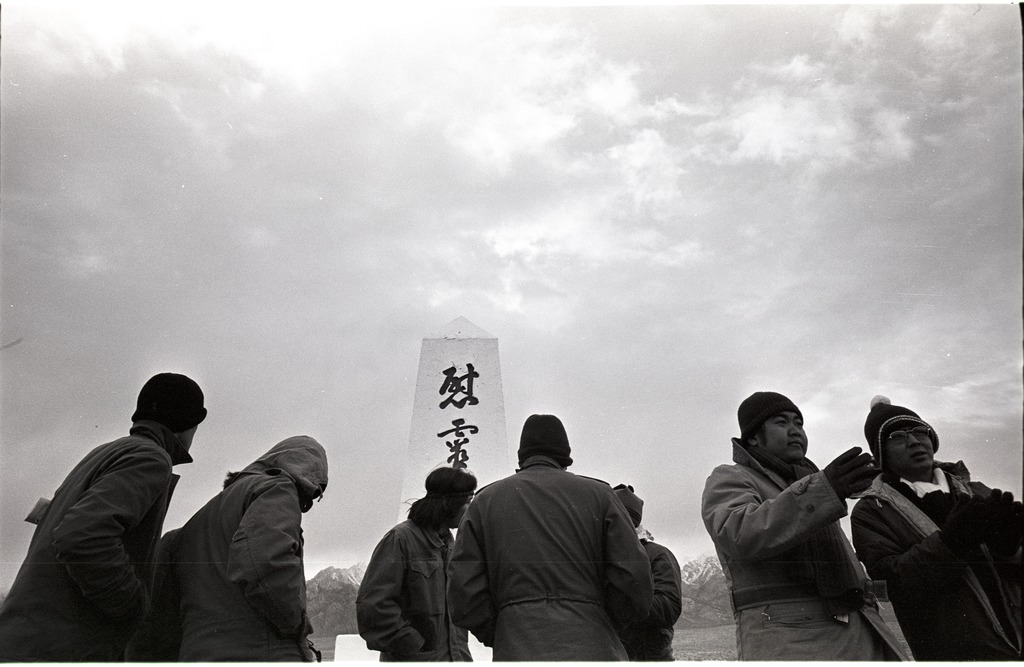 Seven Japanese Americans standing in front of the Manzanar cemetery monument.