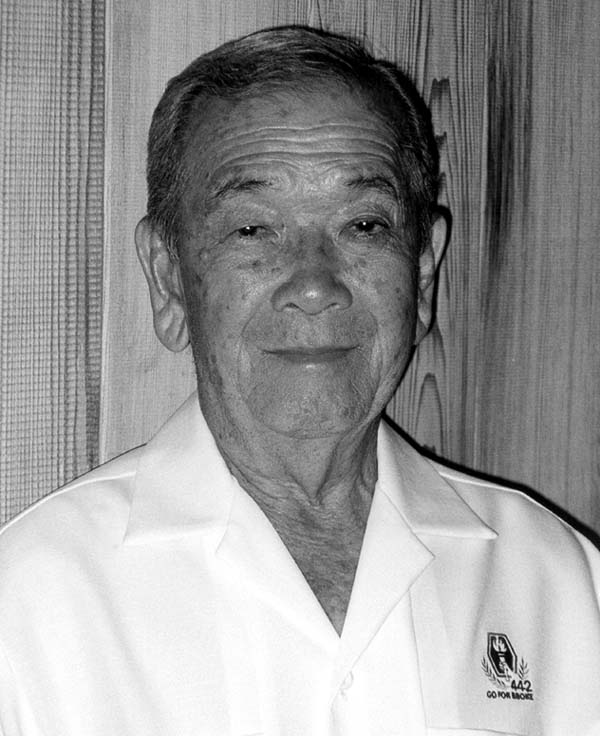 Portrait of Yukio Okutsu wearing a white colored shirt with 442nd/Go For Broke insignia on the chest.